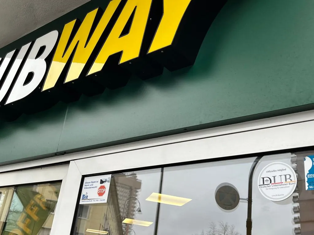 Shop window of a Subway restaurant with a plaque on the glass
