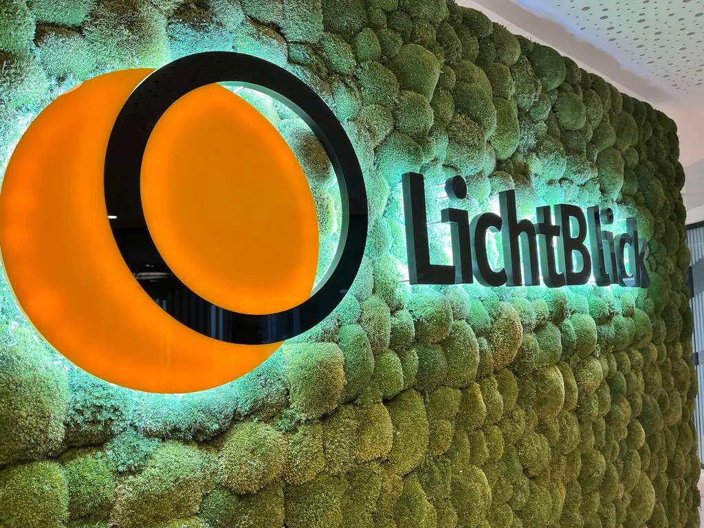 Leuchtendes LichtBlick-Logo auf einer Mooswand